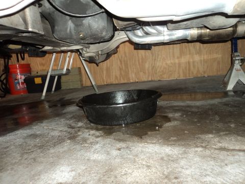 2004 Mercury Grand Marquis - Undercarriage view of a vehicle being serviced, with an oil drain pan catching fluid.