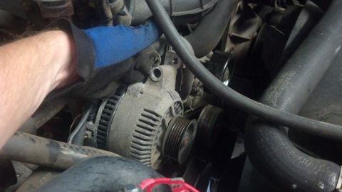 1995 Ford Bronco - Close-up view of an alternator within a vehicle's engine compartment.