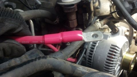 1995 Ford Bronco - A mechanic works on the electrical system of a vehicle, focusing on the alternator and battery cable connection.