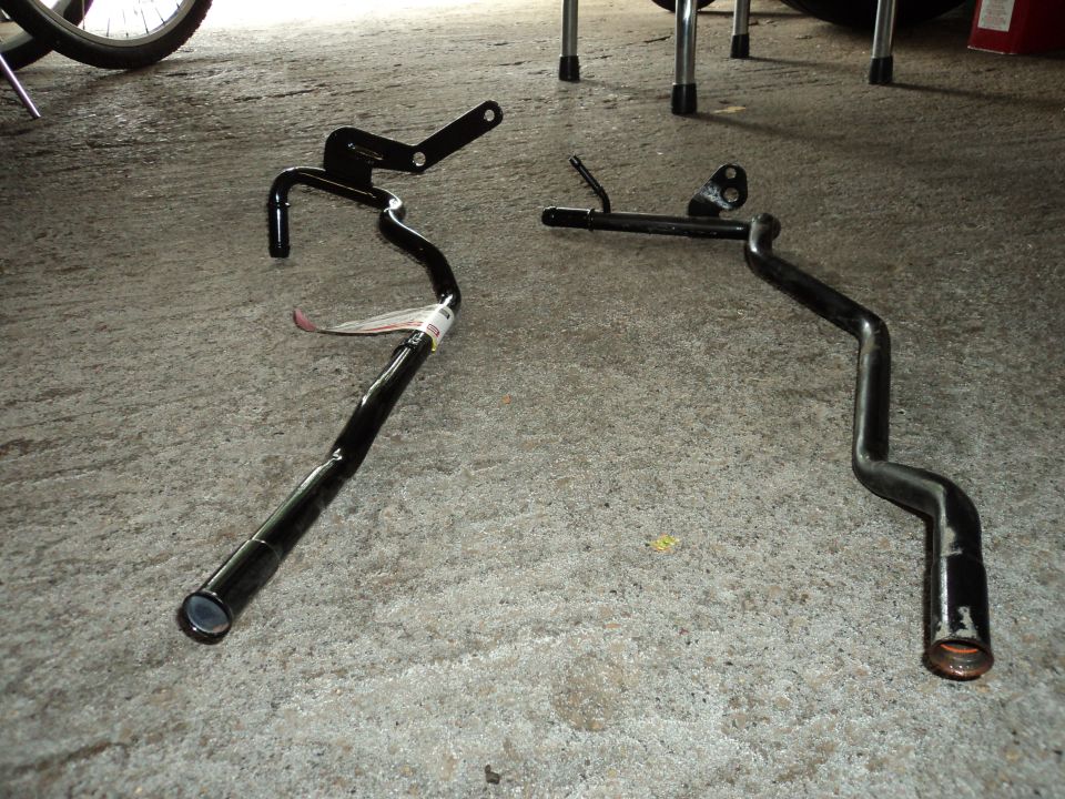 Two black metal pipes on concrete, one with a tag