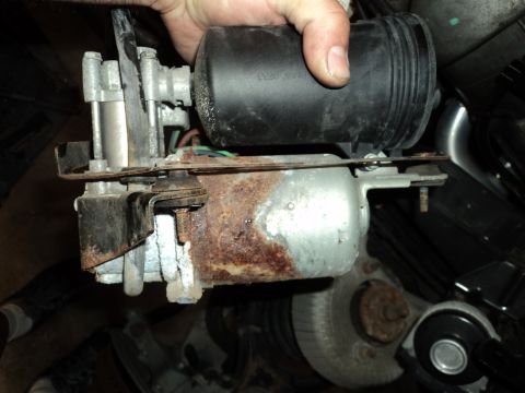 2004 Mercury Grand Marquis - Rusty automotive component with a black reservoir and motor, held by a hand.