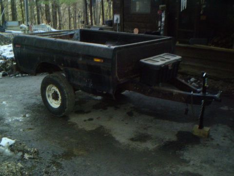 1979 Ford Bronco - A trailer constructed from a black pickup truck bed is parked outdoors, showing its side profile.