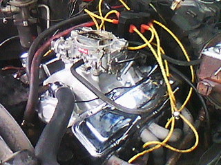 1975 Chevrolet Chevelle - The engine bay features a V8 engine with a carburetor and chrome accents, along with yellow spark plug wires.