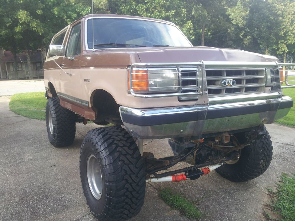 Lifted two-tone brown and tan SUV with large off-road tires and CAT grille emblem
