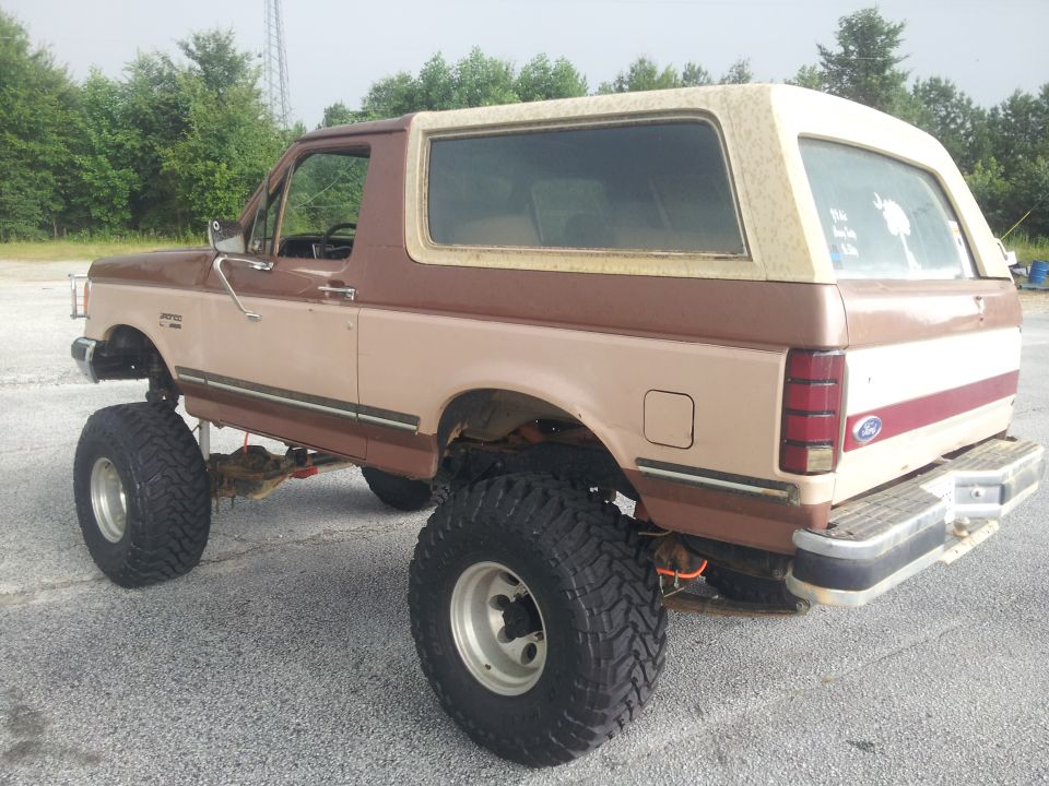 Lifted 1987 Ford Bronco, two-tone brown and tan, with large off-road tires