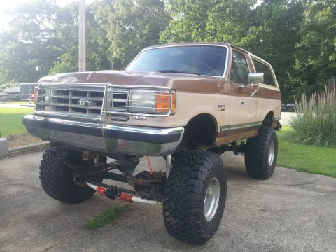 1988 Ford Bronco - This lifted Ford Bronco features a two-tone paint job and aggressive off-road tires.