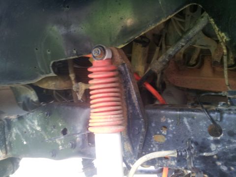 1988 Ford Bronco - Close-up view of suspension components, including a red-booted shock absorber.