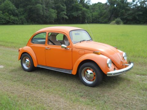 1992 Ford Bronco - This orange Volkswagen Beetle is seen from a three-quarter front view in a grassy outdoor setting.