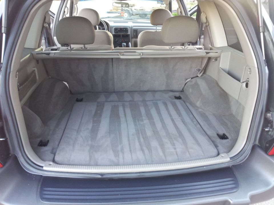 Back cargo area of a 2002 Jeep Grand Cherokee, showing the carpeted floor and side panels