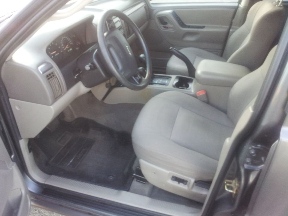 Gray fabric seats and dashboard of a 2002 Jeep Grand Cherokee, viewed from the passenger side door