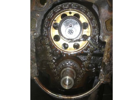 1978 Ford Bronco - Close-up of engine timing components, showing a chain and sprockets coated in grease.