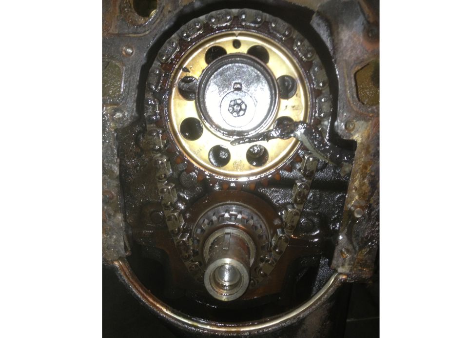 Timing chain and gears inside an engine block, covered in oil