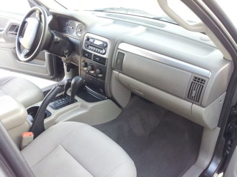 2002 Jeep Grand Cherokee - The interior of a 2002 Jeep Grand Cherokee features a light gray dashboard, center console, and cloth seats.