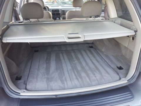 2002 Jeep Grand Cherokee - The rear cargo area of a 2002 Jeep Grand Cherokee, showing the carpeted floor and retractable cargo cover.