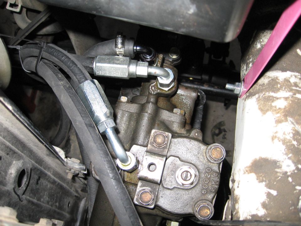 Close-up of a power steering pump with hoses attached. Part number 60020 is visible