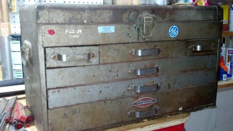 2004 Aston Martin Virage - A vintage metal toolbox shows signs of age and use, brand logos and handwritten markings.