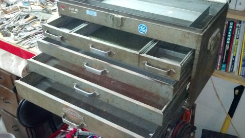 2004 Aston Martin Virage - A vintage GE toolbox with several drawers pulled out, revealing its internal metal structure and handles. Tools and other items are visible…