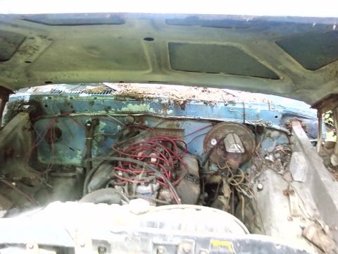 1974 Dodge Challenger - View into the engine bay of a weathered blue vehicle, showing engine components and wiring.