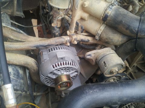 1988 Ford Bronco - Close-up view of an alternator and various engine hoses, showing signs of wear and dirt.