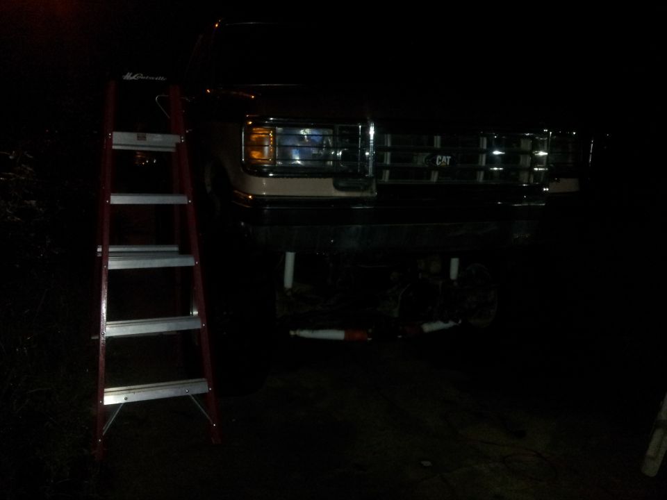 1988 Ford Bronco front end, grille has CAT emblem. Red ladder on left