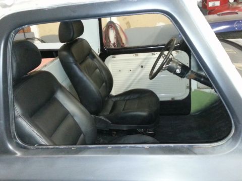 1967 Ford F-100 - The interior of a truck shows black leather seats and a steering wheel, viewed through the open door frame.