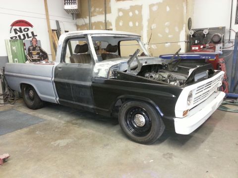 1967 Ford F-100 - This 1967 Ford F-100 pickup is in a workshop, showing its engine bay and unfinished body panels.