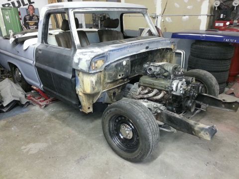 1967 Ford F-100 - This truck is in a garage, appearing to be undergoing restoration or repair work with its engine exposed.