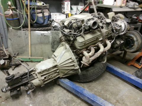 1967 Ford F-100 - Engine and transmission assembly suspended on a lift in a workshop environment.