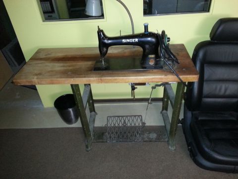 1967 Ford F-100 - A vintage Singer sewing machine sits on a wooden table, next to a car seat in a room.