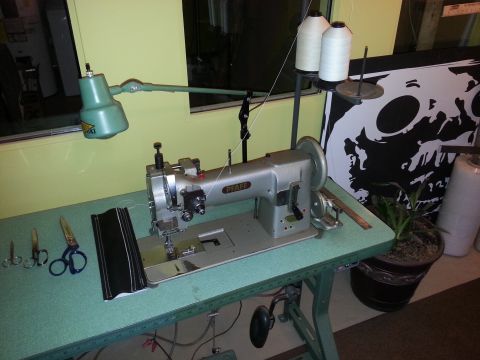 1967 Ford F-100 - A Pfaff sewing machine is set up on a table with various sewing supplies and a decorative poster in the background.