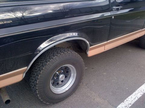 1994 Ford Bronco - Close-up of a 1994 Ford Bronco's rear wheel and fender area with two-tone paint.