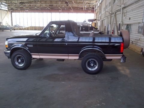 1994 Ford Bronco - Side profile of a black 1994 Ford Bronco with tan trim, parked indoors.