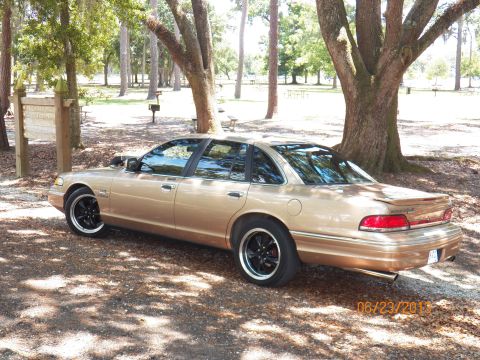 1993 Ford Crown Victoria - A gold 1993 Ford Crown Victoria sedan is parked in a wooded area, with a timestamp of 06/23/2011 visible.
