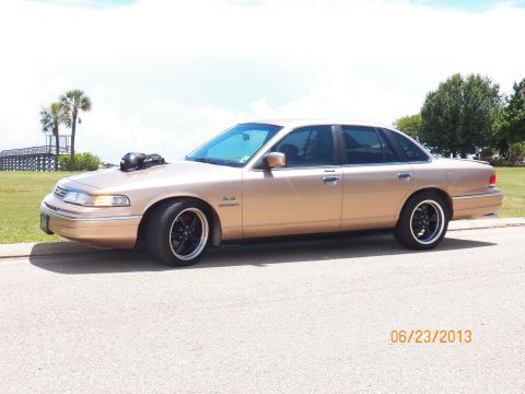 1993 Ford Crown Victoria - A modified 1993 Ford Crown Victoria is shown from the side with a prominent hood scoop and custom wheels.