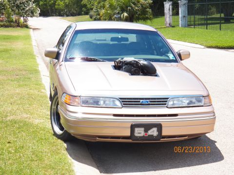 1993 Ford Crown Victoria - A gold 1993 Ford Crown Victoria is parked on a residential street, modified with a prominent supercharger.