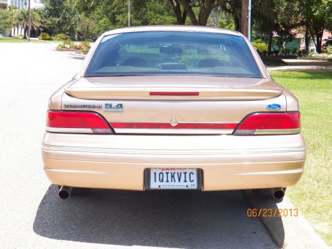 1993 Ford Crown Victoria - Rear view of a gold 1993 Ford Crown Victoria sedan, a spoiler and dual exhaust pipes.