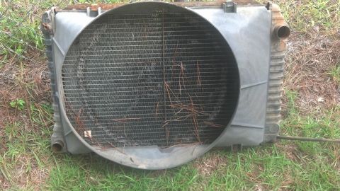 1983 Ford F-250 - Radiator and fan shroud assembly, likely for a truck, with debris on the fins.