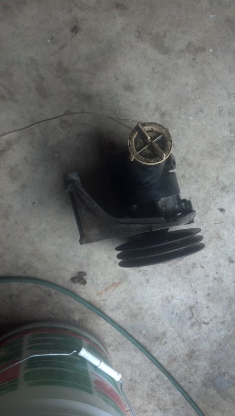 1983 Ford F-250 - A water pump pulley assembly is shown resting on a concrete surface.