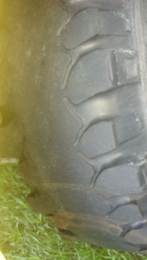 1983 Ford F-250 - The image shows a close-up of a tire's tread, with grass visible at the bottom and a watermark for Supermotors.net.