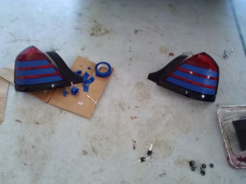 2008 Ford Crown Victoria - Two car tail lights are disassembled on a concrete surface with blue tape and screws scattered around.