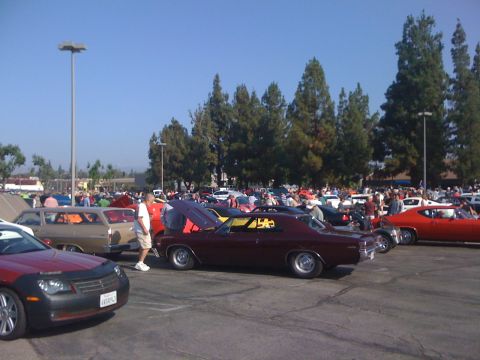1964 Ford Ranchero - A car show with numerous vehicles and attendees under a clear blue sky.