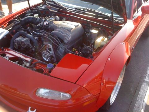 1964 Ford Ranchero - Engine bay of a red sports car with aftermarket fender flares is visible.