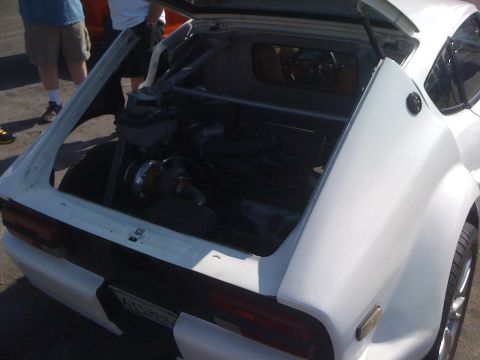 1964 Ford Ranchero - The rear of a white car is shown with the trunk open, exposing engine components and a roll cage.