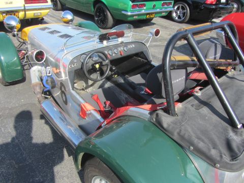 1964 Ford Ranchero - A custom open-top sports car is parked in a lot with other vehicles visible in the background.