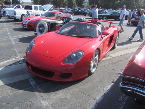 1964 Ford Ranchero - A red Porsche Carrera GT is parked at a car show with other vehicles visible.