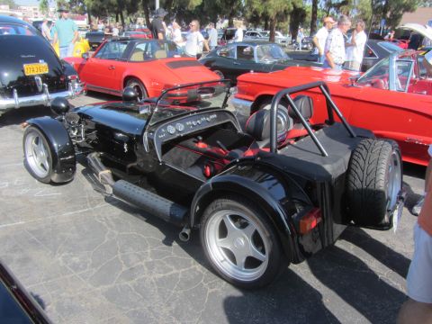 1964 Ford Ranchero - A black sports car with a spare tire on the back is parked at an outdoor car show.