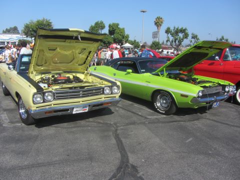1964 Ford Ranchero - Two classic American muscle cars, a yellow Plymouth and a green Dodge, are displayed with their hoods open at an outdoor event.