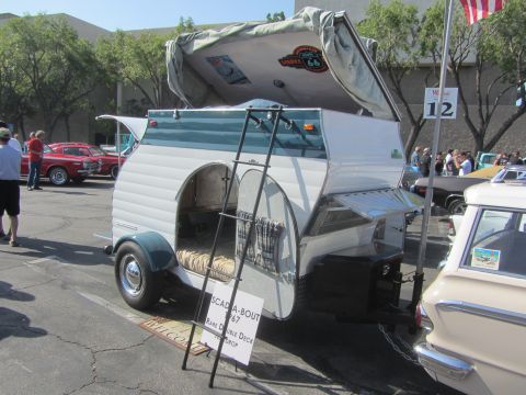 1964 Ford Ranchero - A vintage Scada-Bout camper trailer is displayed at an outdoor event with other cars.