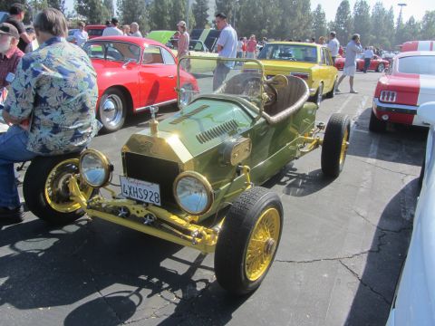 1964 Ford Ranchero - A vintage-style car with gold accents and wire wheels is displayed at an outdoor event alongside other vehicles.