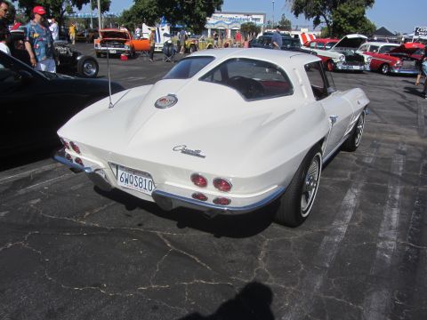 1964 Ford Ranchero - White 1963 Corvette coupe seen from the rear, quad taillights and a chrome bumper.
